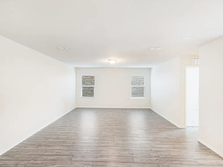 Spacious room featuring wood-finish flooring, white walls, and dual windows