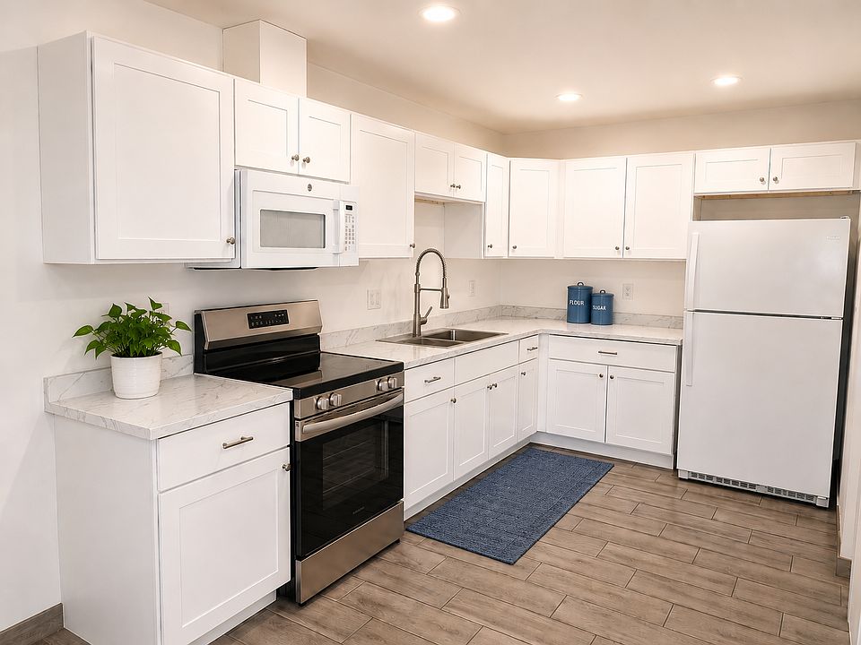 Fully remodeled kitchen featuring brand new premium shaker cabinetry, beautiful marble-look countertops, and new stainless steel and matching appliances. Bright recessed LED lighting highlights the seamless wood-look tile flooring.
