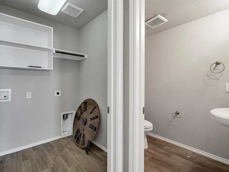 Dedicated laundry space featuring built-in shelving, a hanging rod, and wood-finish flooring