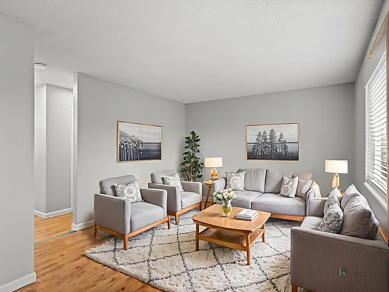 Inviting living room with modern decor, featuring plush gray seating, elegant artwork, and abundant natural light.