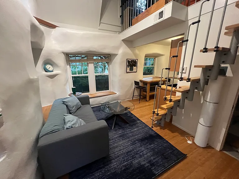 Private detached tiny house with a bright two-story living area, vaulted ceiling, sculpted straw-bale walls and brand-new furnishings.