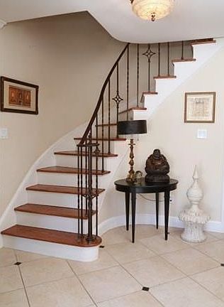 Foyer with delicately curved stairway, original wrought iron ban