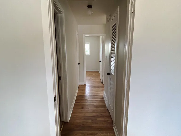 Hallway connecting the first bedroom to the bathroom, storage closet, linen closet, and second bedroom.