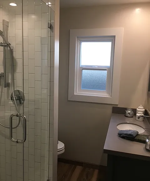 Unit 11- remodeled white subway vertical tile shower with handheld shower head