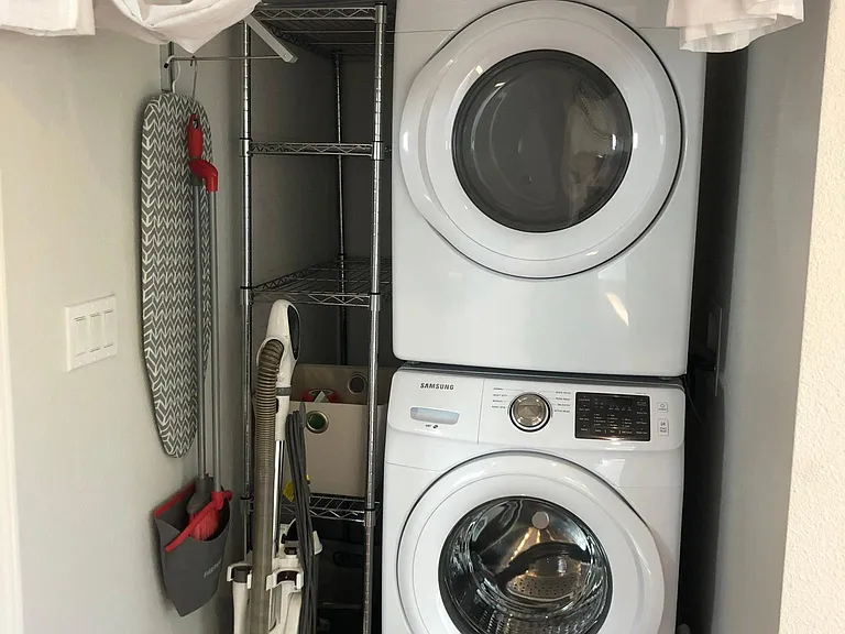 Newer washer and dryer with iron, vacuum, and laundry/pantry storage.