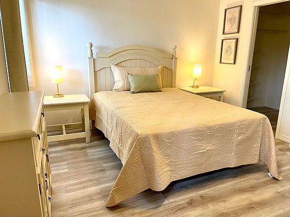 Queen bed with two end table complete with bedside lamps, dresser and black out drapes