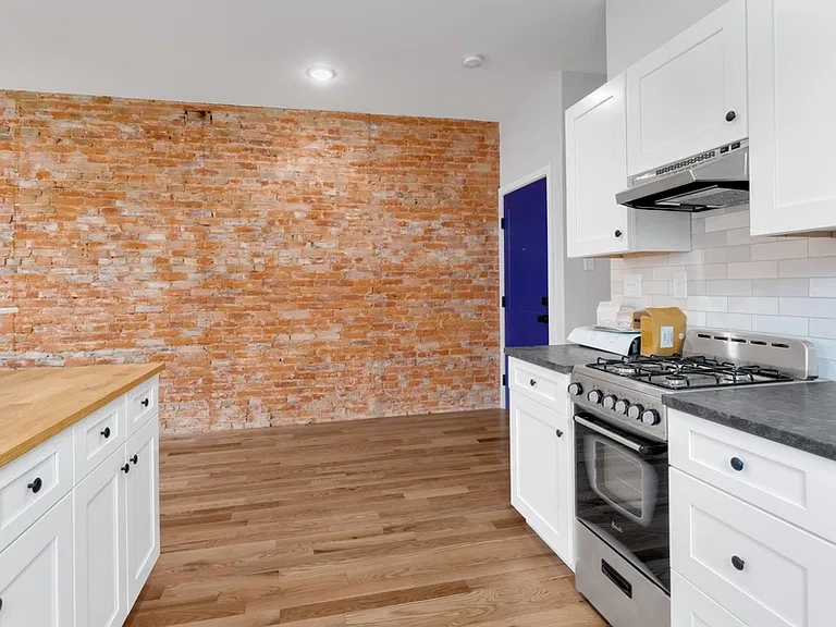 Modern kitchen has tile backsplash, stainless steel appliances, and shaker cabinets.