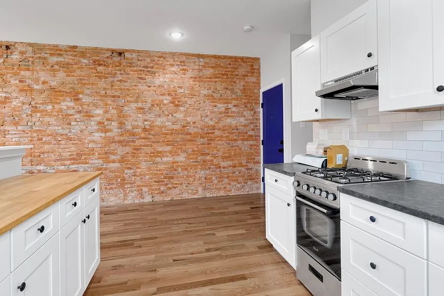 Modern kitchen has tile backsplash, stainless steel appliances, and shaker cabinets.