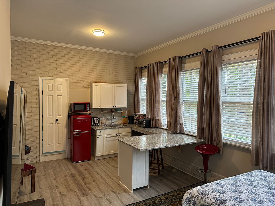 Kitchenette with lots of counter space and large windows with both curtains and shades.