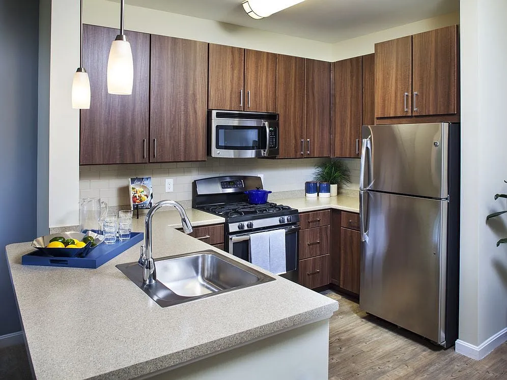 Classic Kitchen with chocolate pecan cabinetry, tile backsplash, laminate countertops, hard surface flooring, and stainless steel appliances - Avalon Framingham