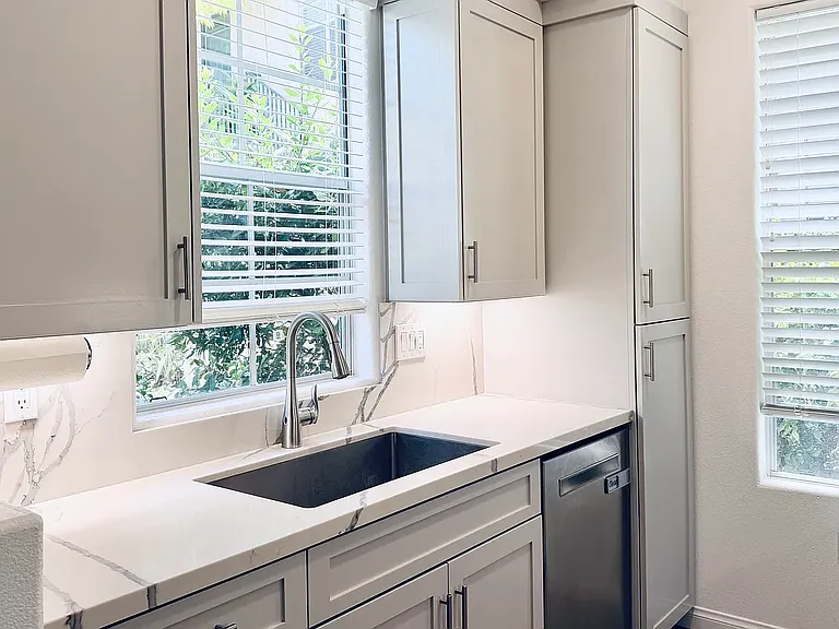 Remodeled kitchen featuring a touchless faucet, newer dishwasher, custom cabinetry, and a large sink