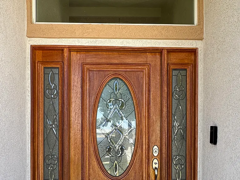 Custom glass feature wooden front door with WiFi Security Camera to answer doorbell remotely via cellular phone. Also has dual cameras; one camera facing the floor to alert if package is picked up.