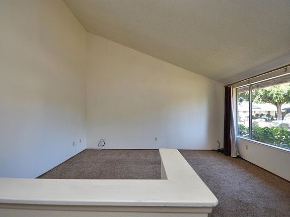 Spacious formal living room with vaulted ceiling and a large picture window facing the front yard