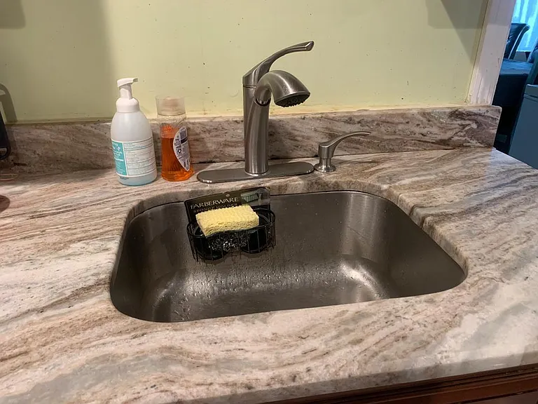 Kitchen sink with a stainless-steel basin, pull-down faucet, and stone-look countertops for everyday meal prep and cleanup.