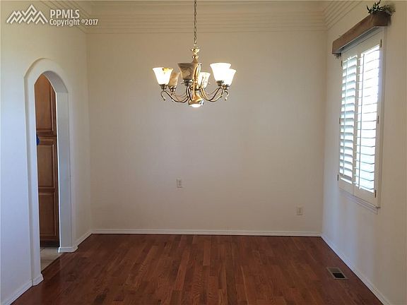 Formal dining room with wood floors and plantation shutters.