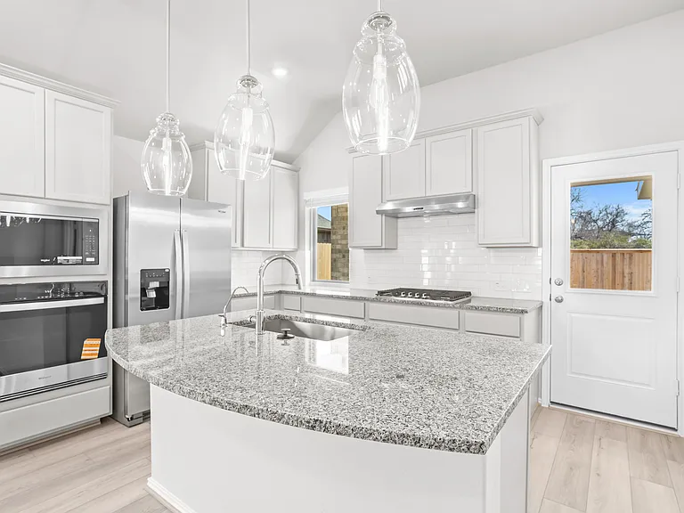 Gourmet kitchen with granite countertop island, white shaker cabinets, subway tile backsplash, pendant lighting, and luxury vinyl plank flooring.