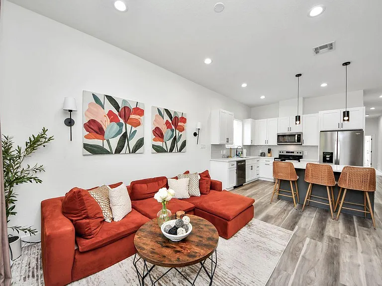 Open-concept living area flows into a kitchen with a large island, bar seating, and stainless-steel appliances.