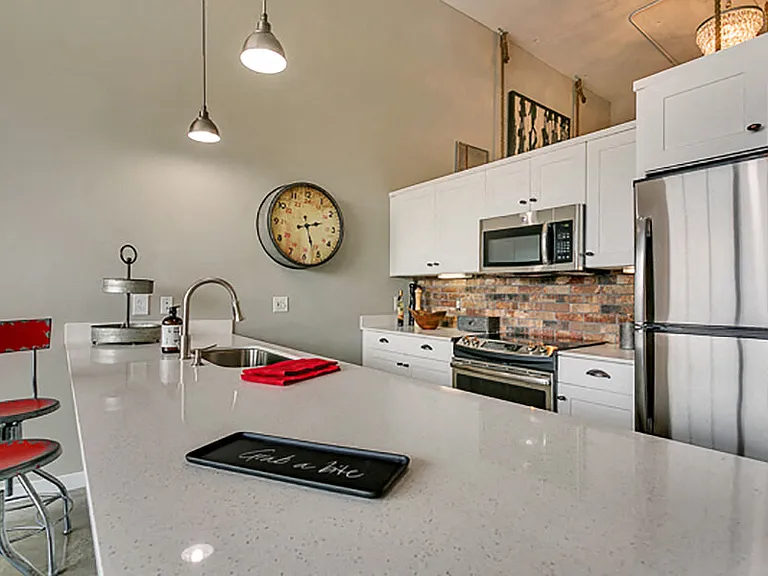 Modern kitchen with white cabinets and brick style backsplash, with white quartz countertop