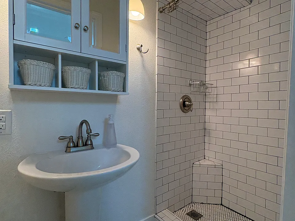 A standup shower, pedestal sink, vanity and toilet provide a comfortable bathroom space.