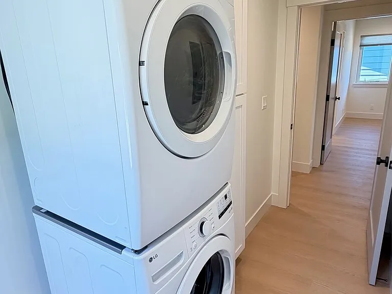Dedicated laundry area with stackable washer and dryer, plus additional storage space.