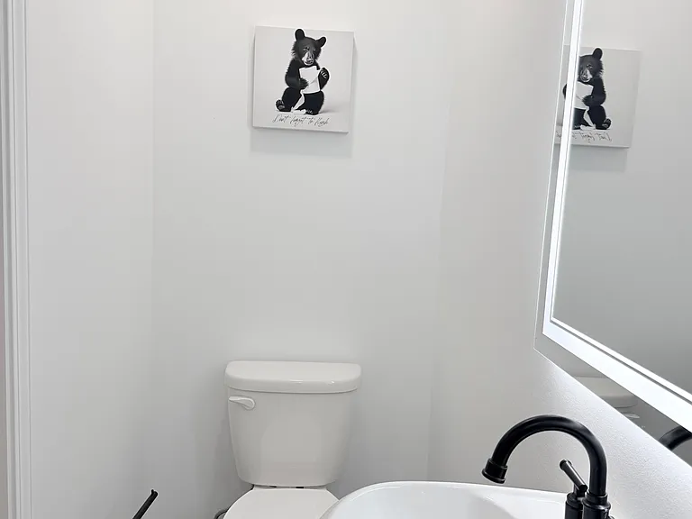 Updated half bath with a pedestal sink, matte-black fixtures, and tile flooringideal for guests and everyday use.