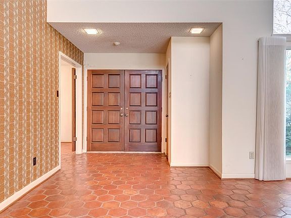 Beautiful solid wood entry doors and honey comb terra-cotta tile throughout the living room and dining room.