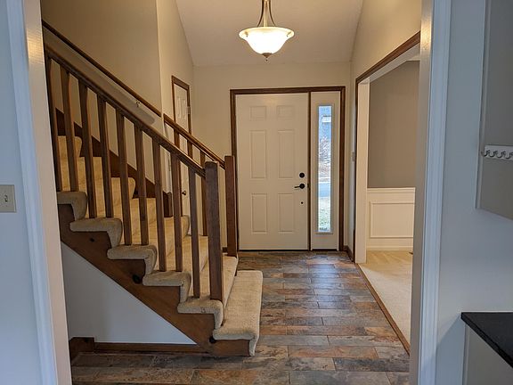 Welcoming entry with slate tile floor and open staircase.