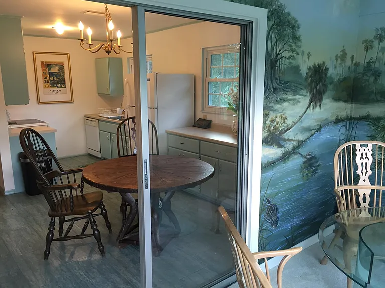 View from sunporch through sliding glass doors to kitchen. No longer a table and chairs on the other side of this carpeted room. Now a desk for your use.