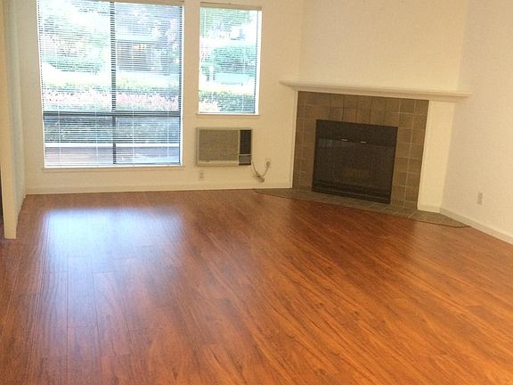 Fireplace and A/C unit in the living room. Wood laminate flooring. Clean!