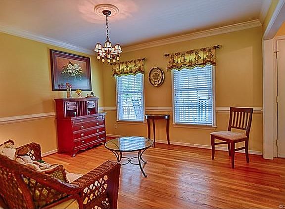 Formal dining room with gleaming hardwood floors, crown mouldings and chair rail.