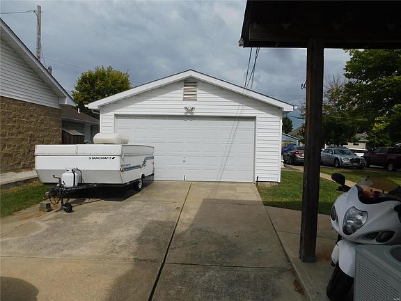 Detached garage with concrete driveway. Additional parking in park