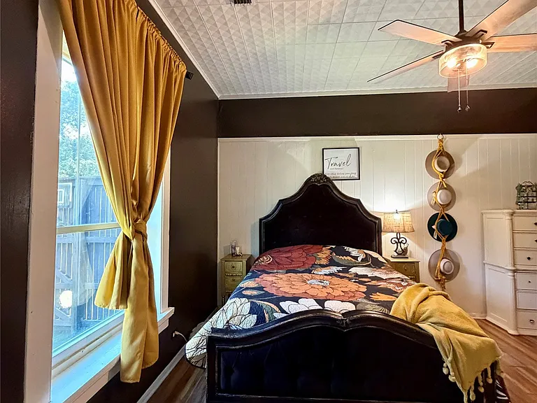 Bedroom featuring wood-finish flooring, a textured white ceiling, and a ceiling fan with integrated lighting