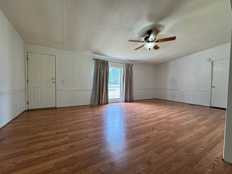 Bright, oversized living room featuring modern LVP flooring, a large bay window overlooking the front yard, and direct access to the front porch. Plenty of space for family gatherings and everyday living.