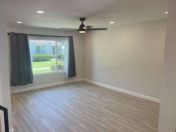 Living room with 6 ceiling lights and fan with ligfht viewed from dining room.
