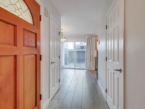 Bright hallway leading to kitchen, dining area, and private patio.