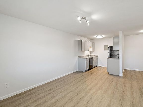 Modern open-concept kitchen and living area with sleek cabinetry, stainless steel appliances, and elegant flooring.