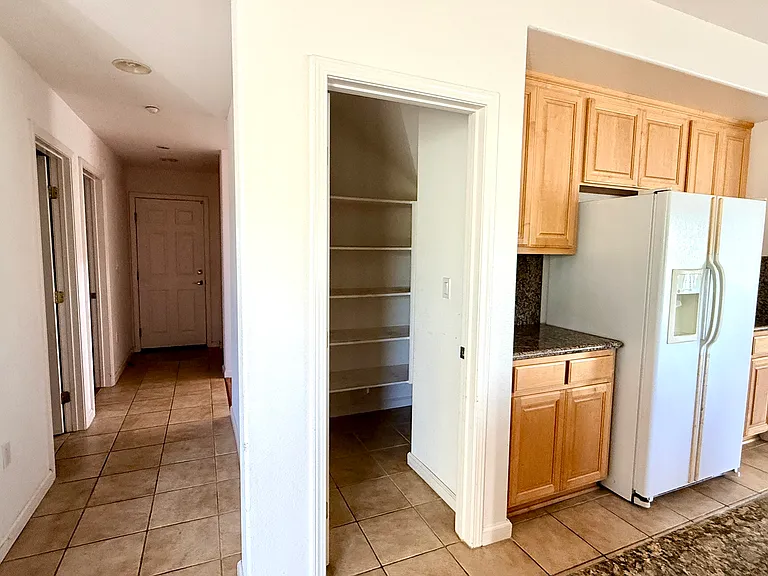 Walk-in pantry with ample storage, refrigerator, and garage access