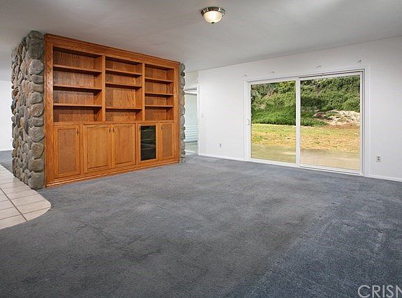 Expansive family room with striking custom-built wood entertainment center/bookcase and easy access to the backyard through the sliding glass doors.