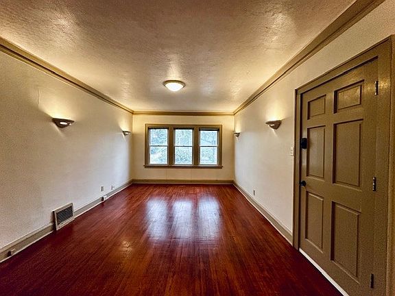 Upon entry, the living room's gleaming hardwood floors draw your eyes towards the windows
