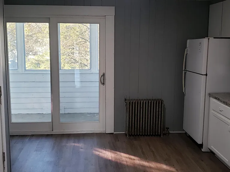 Kitchen includes refrigerator, gas stove and exits to sun porch via sliding glass door.