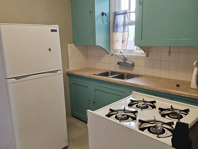 kitchen from living room with gas stove, fridge and small microwave.