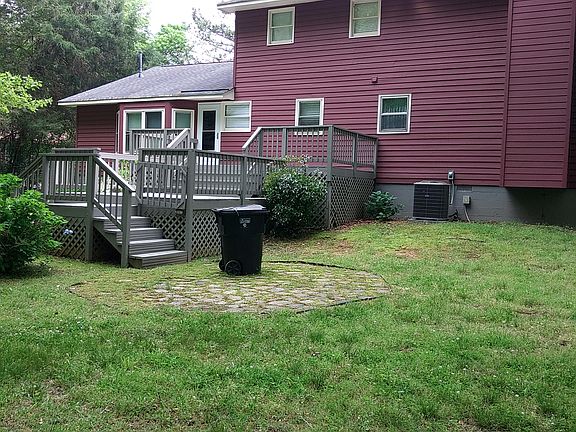 Back of house with large deck, patio and yard is fenced.