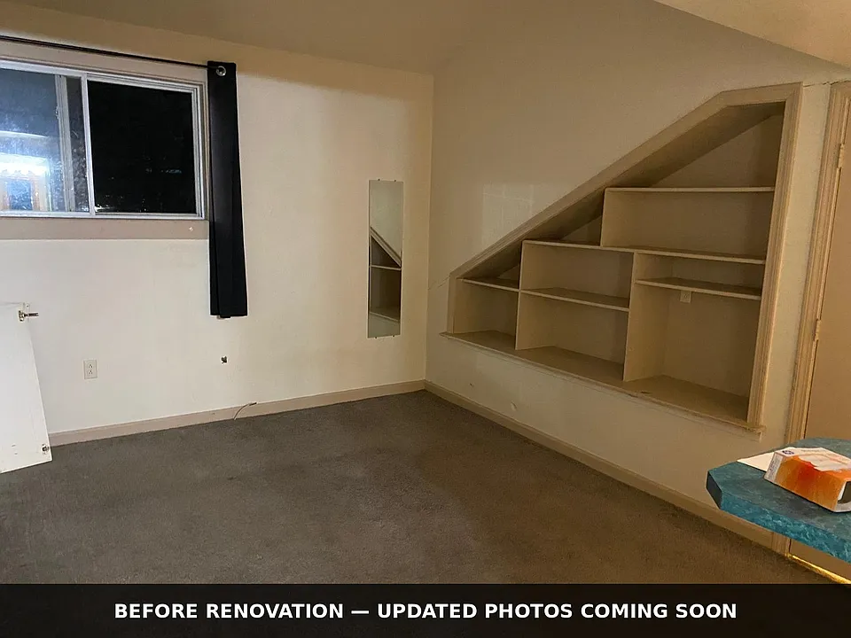 Living area with extensive built-in shelving for books, decor and storage. BEFORE renovation _ new flooring and fresh paint coming.