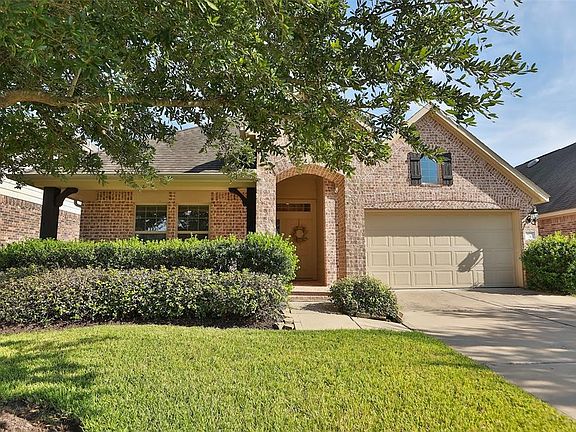 STRIKING CURB APPEAL: A lot of detail went into the brick work on this home, from the arched entry to the varied brick patterns on the face of the garage. Large timbers accent the front porch and compliment the board and batten shutter on the window 