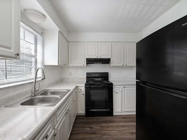 Modern kitchen with sleek black appliances, polished countertops, and bright cabinetry offering ample storage and charm.