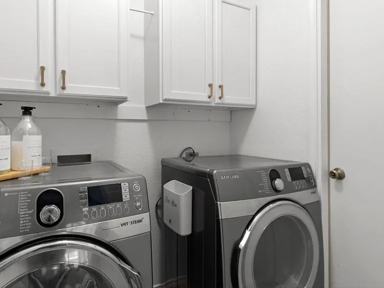 Laundry room with full-sized stainless-steel washer, dryer and plenty of storage.