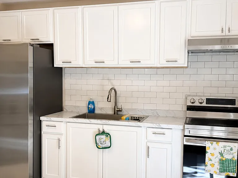 Kitchen features ample white shaker cabinetry, subway-tile backsplash, and stainless-steel range for everyday cooking.
