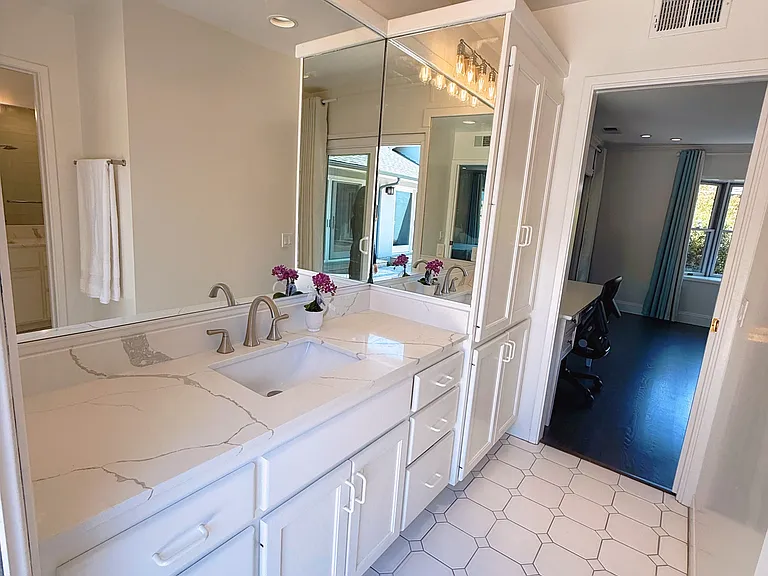 Primary bathroom with new countertop, mirror and lighting features; Primary bathroom with sliding door to backyard
