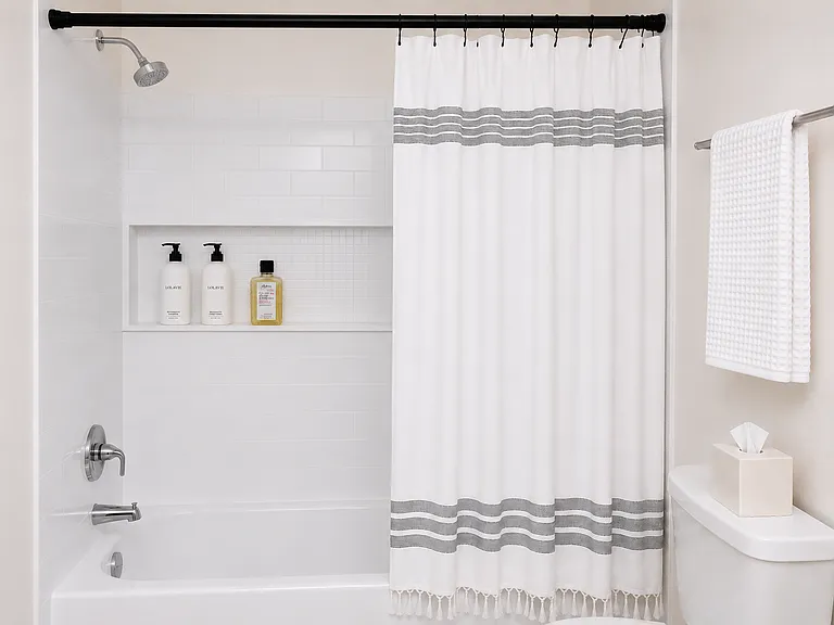 All white tiled bath/shower.