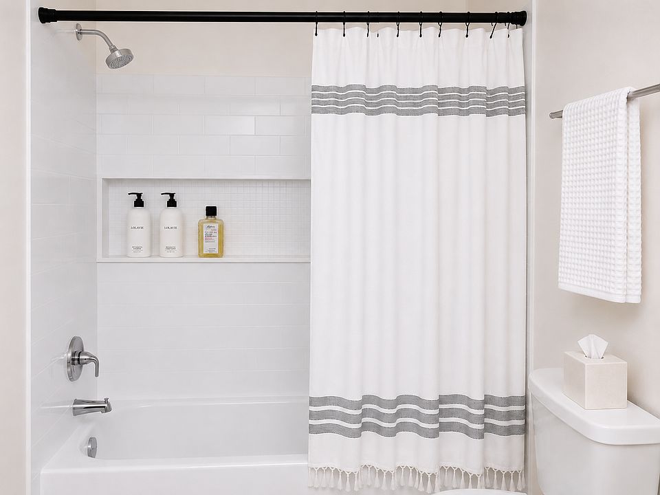 All white tiled bath/shower.
